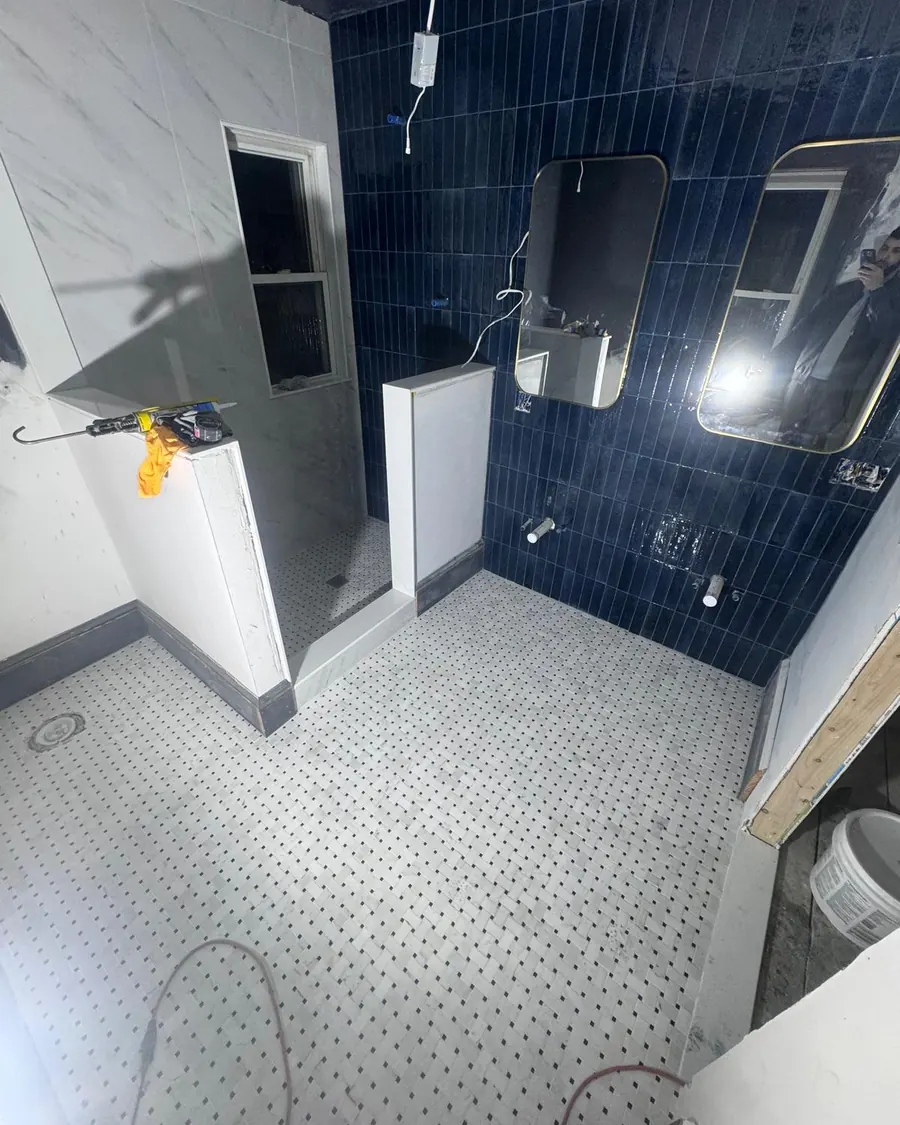 Blue tile shower wall and mosaic floor tile going in during a bathroom remodel