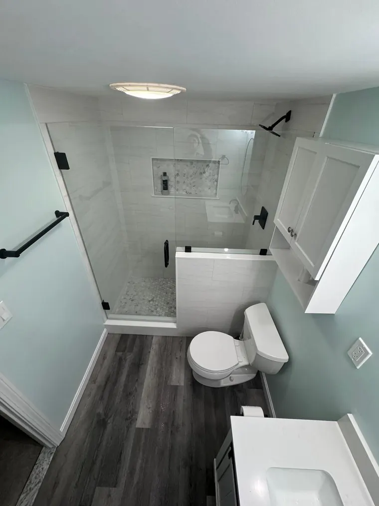 Alcove tub with a glass panel and a wood look tile floor