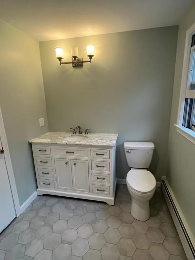 Bathroom vanity on hexagon floor tile with green painted walls