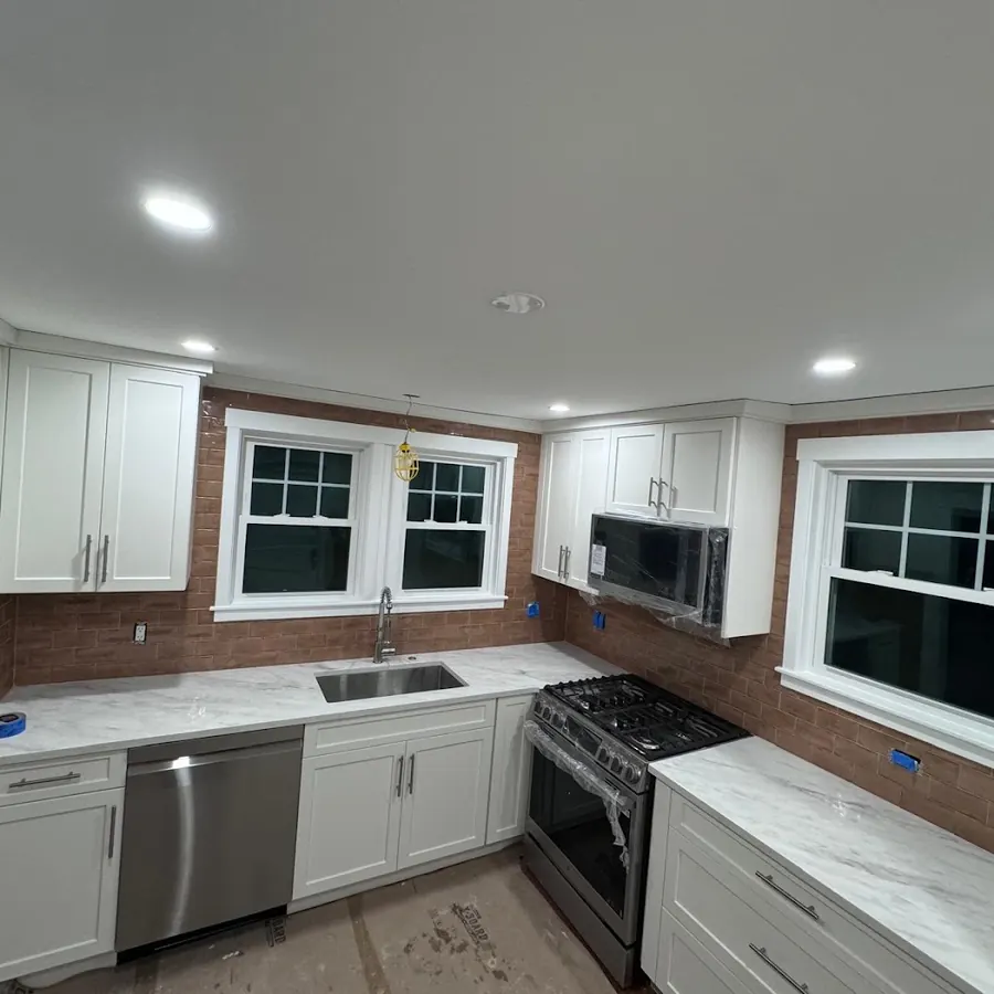 White shaker kitchen with quartz counters and a tiled backsplash