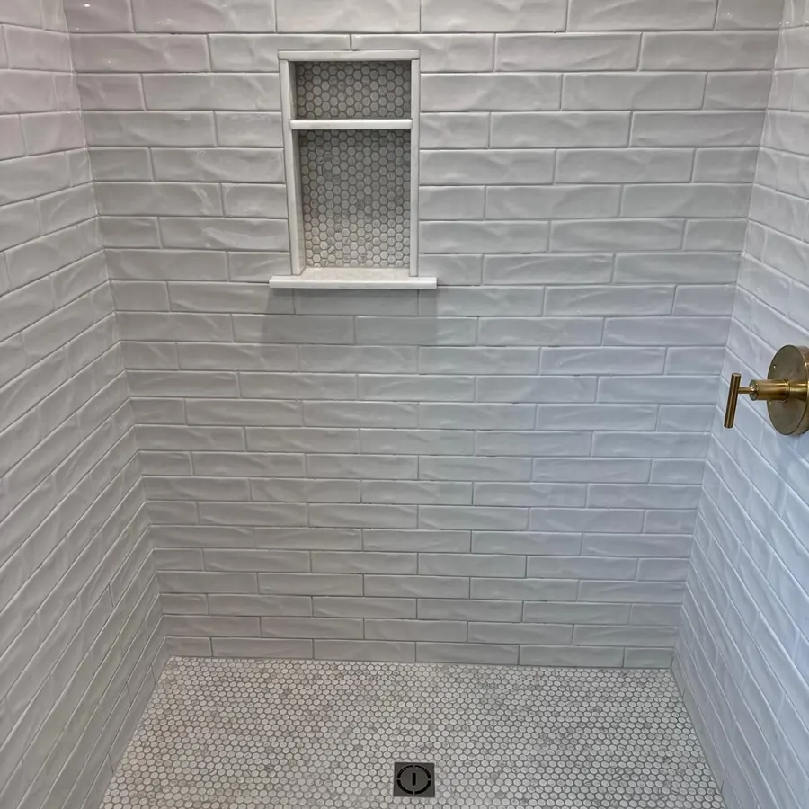 White picket tile shower wall over a mosaic tile shower pan