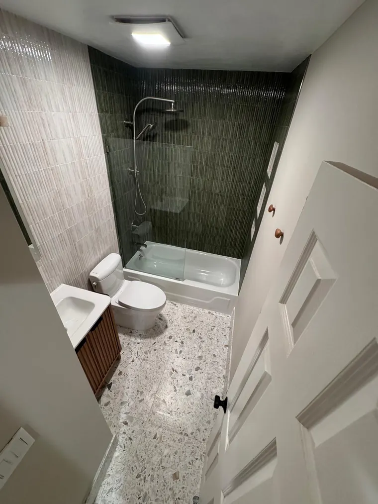 Terrazzo look floor tile with a green tile shower in a remodeled bathroom