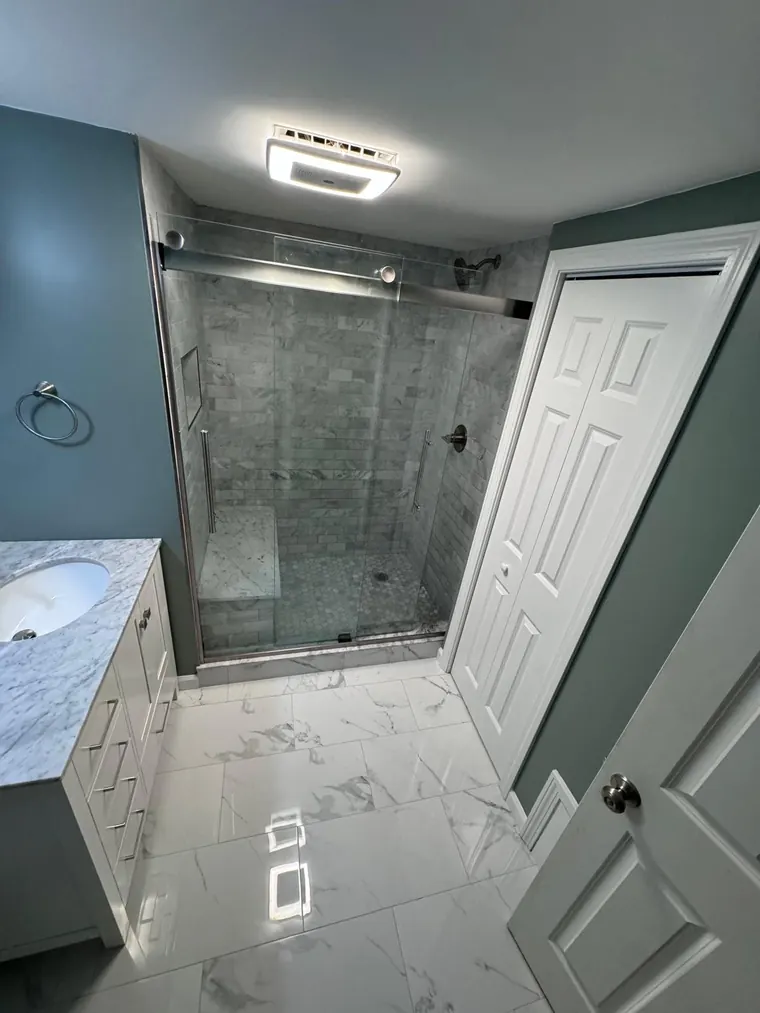 Marble look floor tile running into a glass shower enclosure
