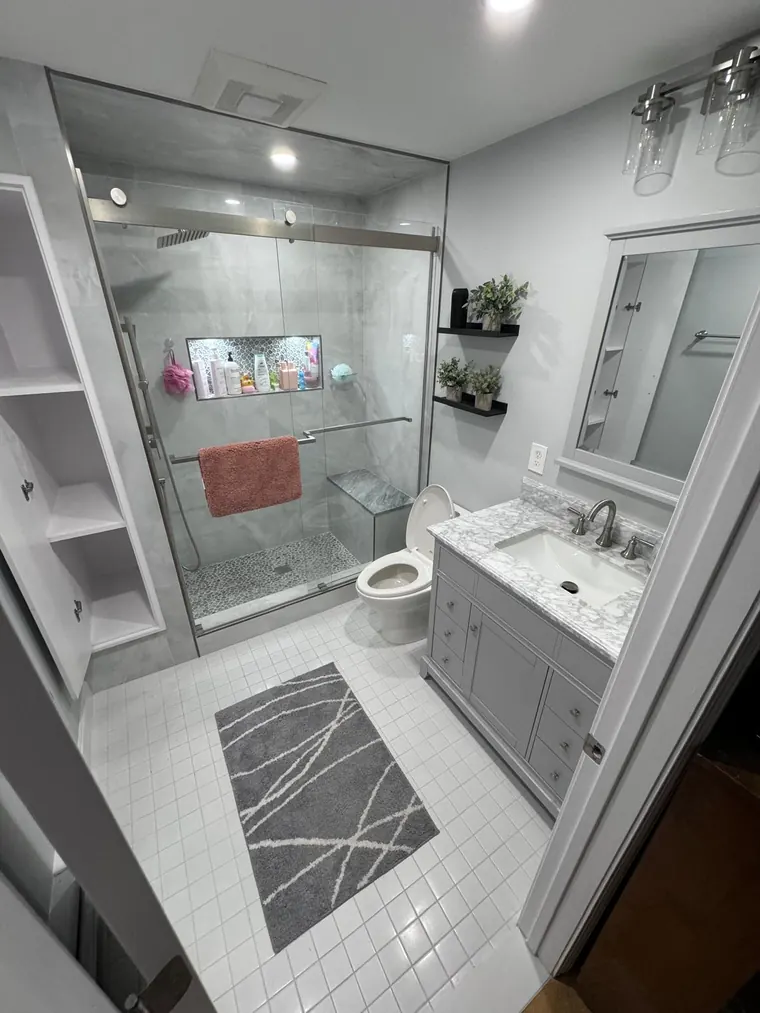 White tiled bathroom with a glass shower and a grey vanity