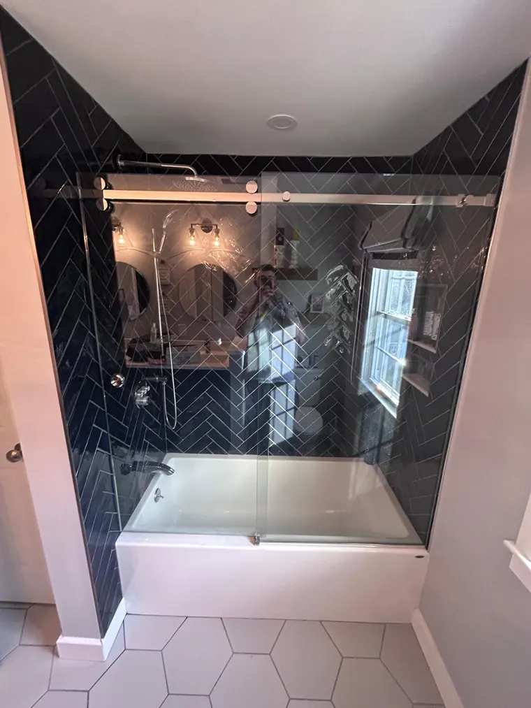 Black herringbone tile surround over an alcove tub