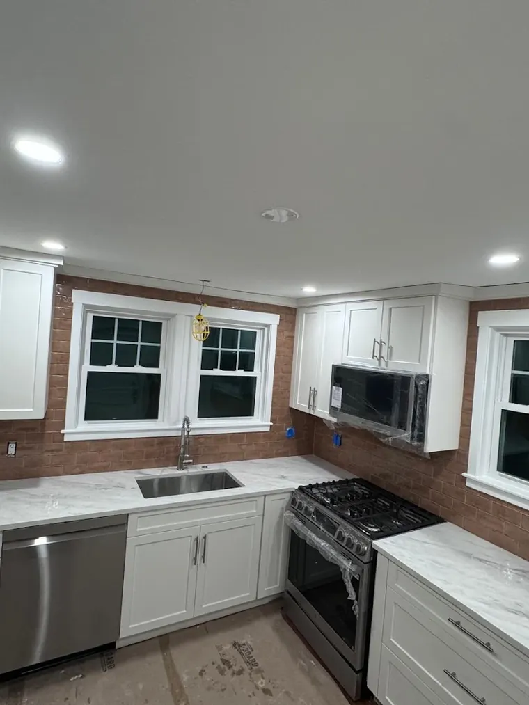 White shaker kitchen with quartz counters and a tiled backsplash