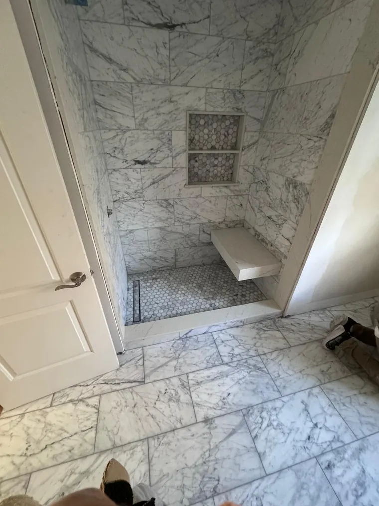 Marble tile shower with a built in bench and a recessed niche