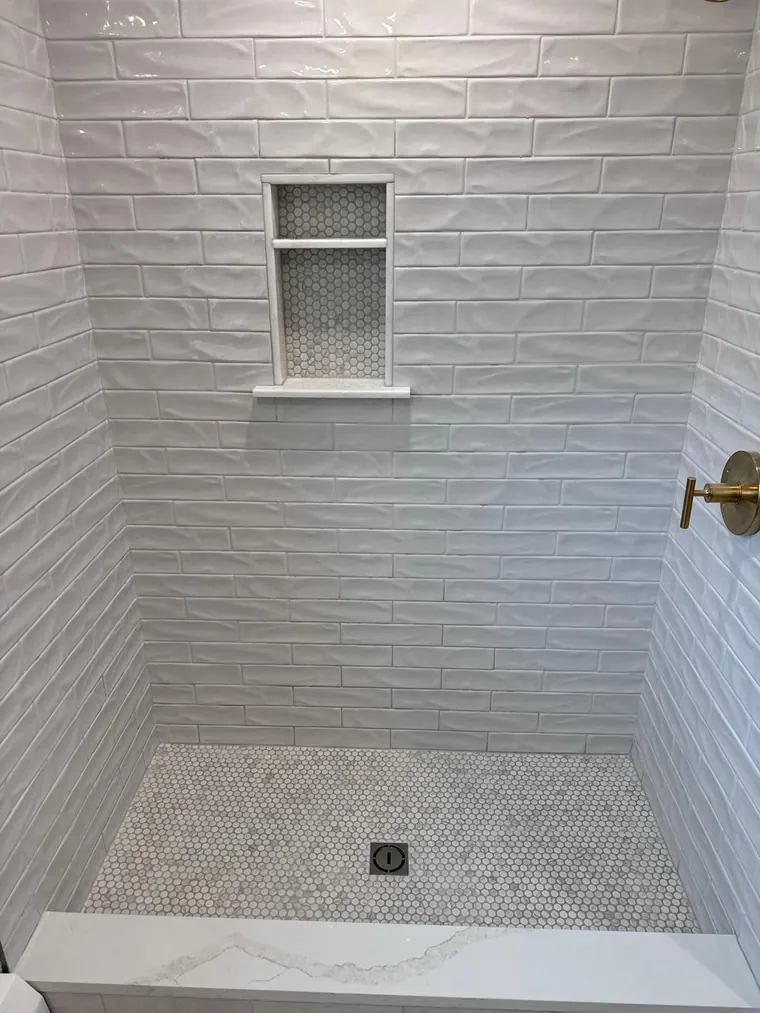 White picket tile shower wall over a mosaic tile shower pan
