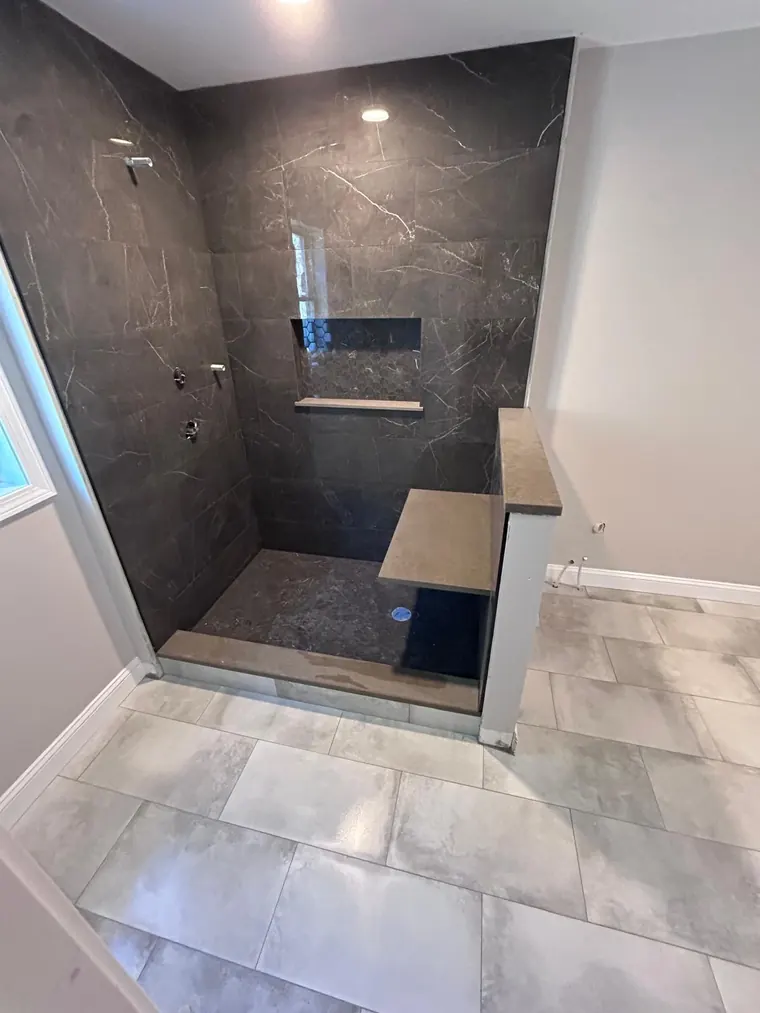 Dark marble look tile shower with a floating bench